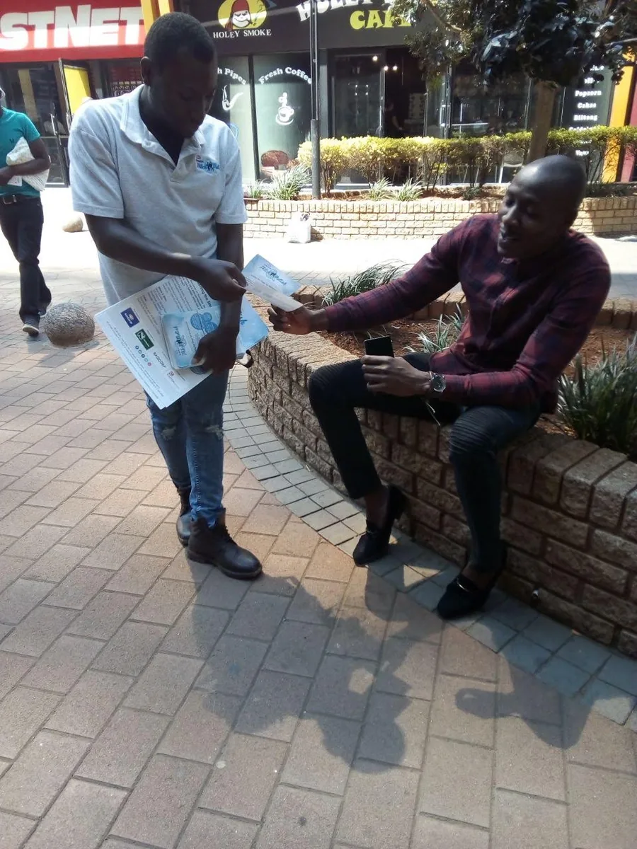 Field promoter handing campaign material to a pedestrian