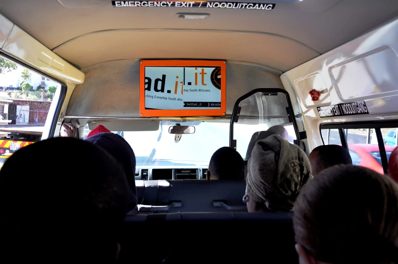 Taxi passengers seated below an AD.IT digital advertising screen