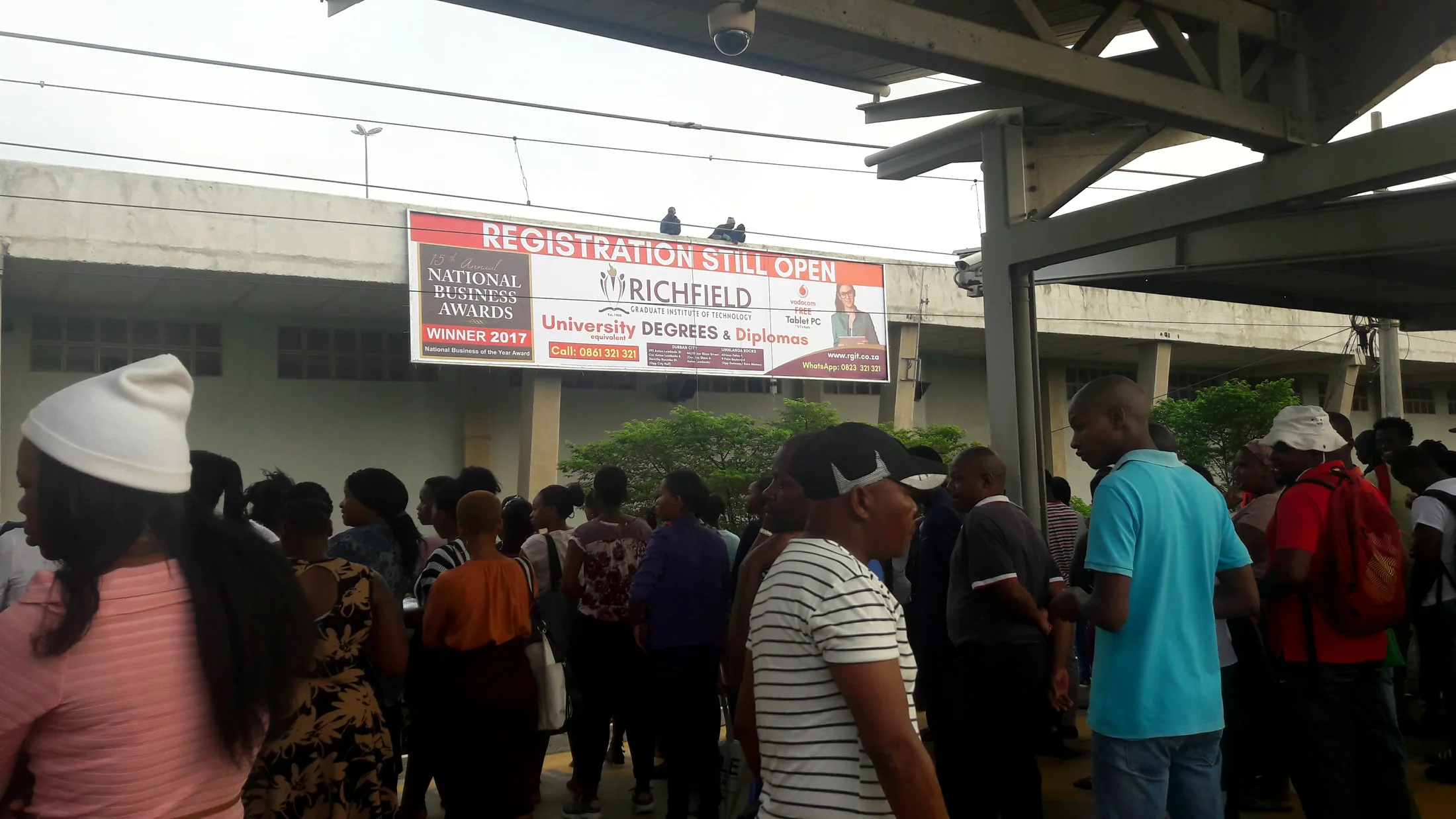 Train station commuters beneath large billboard media placements